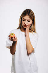 Young girl isolated on white background having toothache holding an apple
