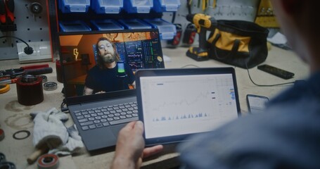 Employee Watching Online Trading Lesson on Laptop, Checking Real-Time Stocks, Exchange Market Charts Using Smartphone and Digital Tablet. Man Remote Learning Trading Working in Workshop. Close Up.
