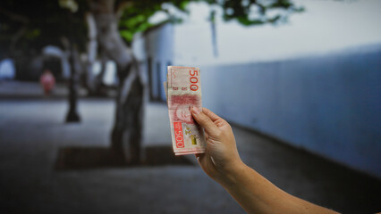 Hand holding swedish krona banknotes in an urban street setting, illustrating modern investment or...