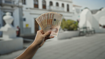 Man holding south korean won banknotes outdoors on a city street showcasing currency and finance...