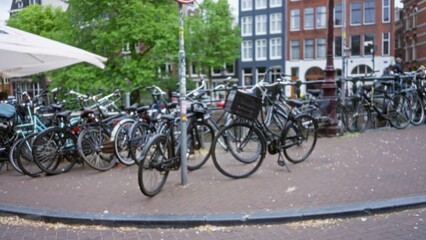 Blurred bicycles and canal scenery create a classic amsterdam vibe with defocused urban backdrop and vibrant greenery.