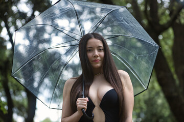 Portrait of a young brunette woman, beautiful, with pale skin, wearing a black dress, covering...