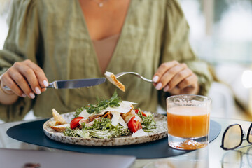 Young woman drinking juice and eating salad on a cafe terrace