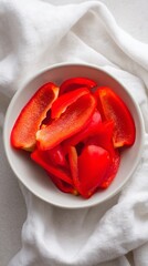 Freshly Sliced Red Bell Peppers in a Bowl on a White Cloth Background