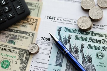 American US dollars money bills and coins with pen and calculator on IRS tax form blanks