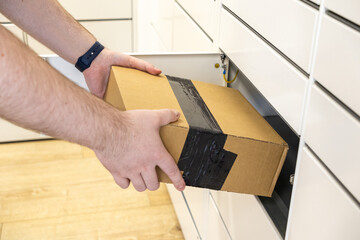 Person retrieving a cardboard package from a white parcel locker, symbolizing convenient e-commerce pickup and secure delivery services