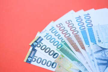 South Korean won money bills in big amount lies on red color table close up