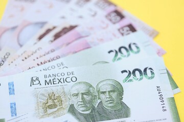 Mexican pesos money bills in big amount lies on yellow color table close up