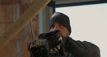 Worker cutting wood with chainsaw, wood splinters flying in slow-motion at 800 fps, focused...