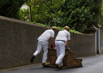The Monte Sledges. two (Carreiros) runners operating a traditional wicker basket car with tourists....