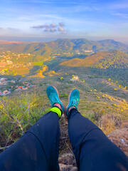 Traveler's legs hang from mountain. Mountains landscape. Legs hanging over cliff in Sierra...