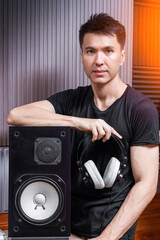 asian handsome male music producer posing with loudspeaker and headphone on audio diffuser background in studio