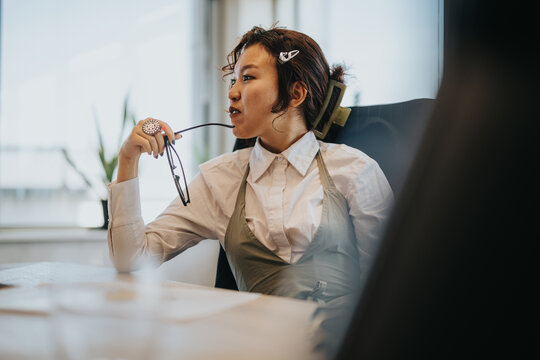 A contemplative businesswoman holds her glasses while sitting in a stylish office. The image portrays a modern and reflective atmosphere, ideal for concepts of thinking, decision-making, and workplace