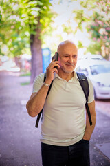 Middle aged man walking on the street and using a smart phone