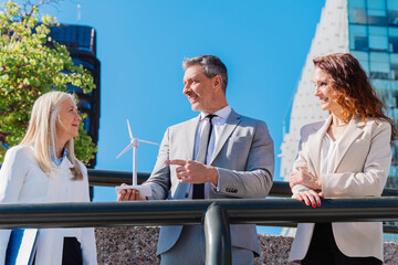 Professional team examining miniature wind turbine, collaborating on sustainable energy project...