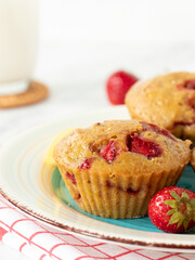 Homemade strawberry muffins on a plate with glass of milk in the background. Close-up.