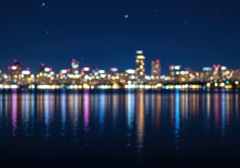 Blurred city lights reflecting on the water at night