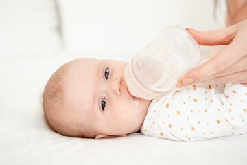 Mom's hand holds a bottle of milk for a newborn baby. Small child with bottle close-up, High quality 4k footage