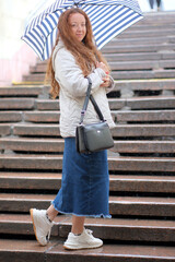 Fototapeta premium Stylish woman with umbrella strolls down rainy city steps