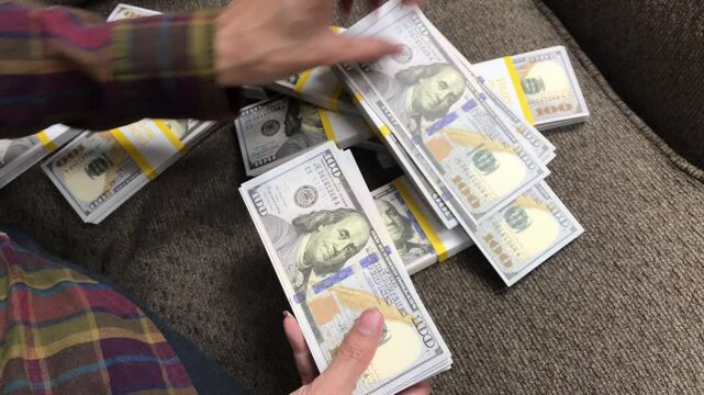 Young Woman Counts Stacks of Cash $100 Bills