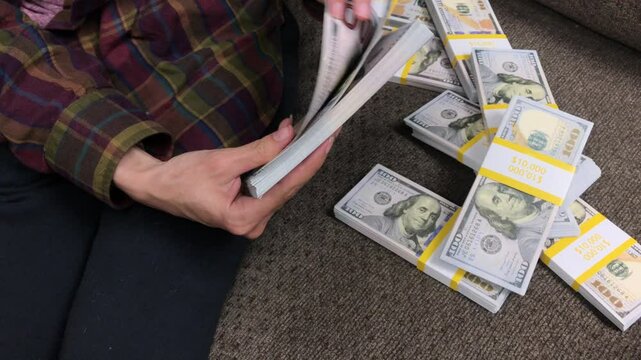 Young Woman Counts Stacks of Cash $100 Bills
