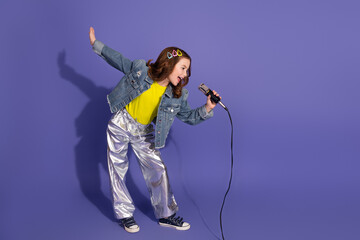 Young girl holding a microphone and singing enthusiastically against a vibrant purple background