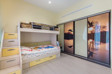Modern design of a children's room with a bunk bed, a staircase with drawers to the second tier, a...
