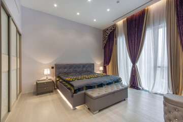 The interior of a spacious bedroom with a luxurious design. Light grey furniture, built-in...