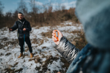 Two hikers enjoy a winter day walk in a snowy landscape, one holding a navigational tool while the other observes.
