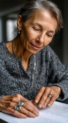 Elderly caucasian female reading braille at home in a cozy setting