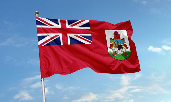 Bermuda national flag with Union Jack and coat of arms featuring a lion and ship on a red field flying in the sky