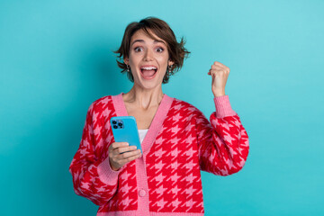 Photo of cheerful lucky lady wear pink cardigan winning game modern device isolated teal color...