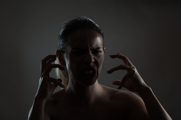 Dramatic portrait of a young woman expressing rage with gesture in low light