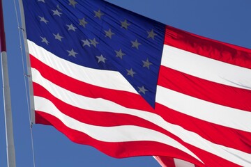 United States American red white and blue flag blowing in the wind against blue sky
