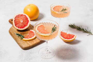 Elegant grapefruit and rosemary cocktails served in crystal glasses with fresh grapefruit slices,...