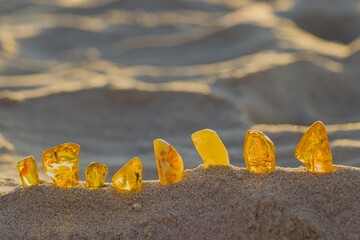 Amber gems in soft colors lit by golden rays on the peaceful beach in Kołobrzeg.