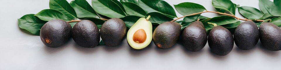 Fototapeta premium A bunch of avocados with one cut open. The avocados are black and the one with the cut open is the only one that is visible