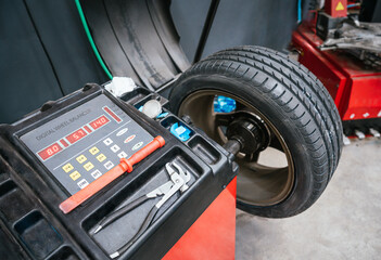 Digital wheel balancer in use at auto repair shop with tire mounted on machine