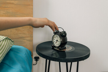 Teenager girl stopping alarm clock in the morning