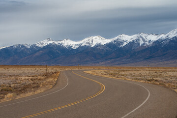 Two lane road and the Sangre de Cristo Mountains, Colorado, USA