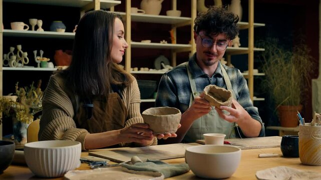 Caucasian woman man couple date handmade master class in pottery workshop potter sculptor artist modeling clay together crafts hobby enjoying handcraft in art studio happy girl guy smiling high five