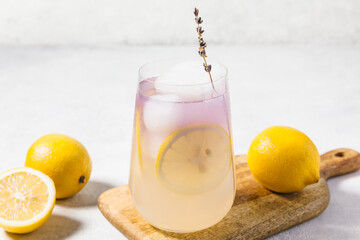 A refreshing lavender lemon lemonade served in a transparent glass filled with ice, garnished with...