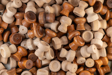 A pile of wooden drawer knobs or handles in various natural shades, showcasing craftsmanship,...