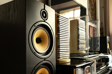 Close-up of a high-end speaker with vintage audio equipment in the background, creating a warm, retro-modern atmosphere in a home audio setup