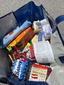 Kitsse, Austria - 25 May 2025: reusable blue shopping bag filled with various groceries from Hoffer store placed on asphalt ground outdoors after shopping. concept of retail, groceries, consumer goods
