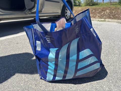 Kitsse, Austria - 25 May 2025: reusable blue shopping bag filled with various groceries from Hoffer store placed on asphalt ground outdoors after shopping. concept of retail, groceries, consumer goods