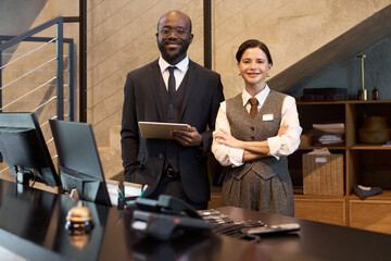 Friendly hotel staff in formal attire greeting guests at reception desk Embracing hospitality with warm smiles and professional demeanor, ready to assist guests