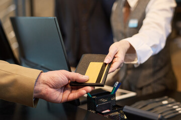 Close-up view of hands holding credit cards at counter during interaction in professional setting wearing formal attire