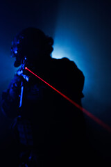 Tactical figure with red laser beam in dramatic low light setting
