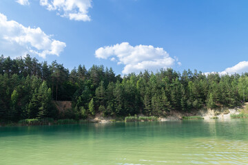 Beautiful summer landscape - a lake surrounded by green trees against a blue sky
